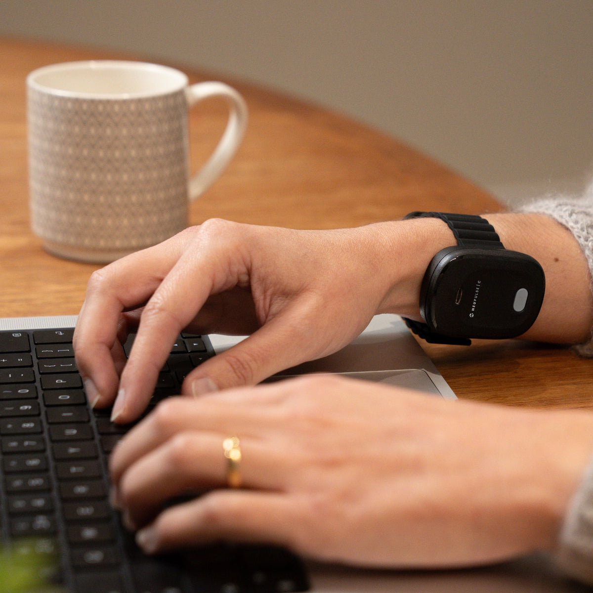 Person typing while wearing the Neupulse C on their wrist