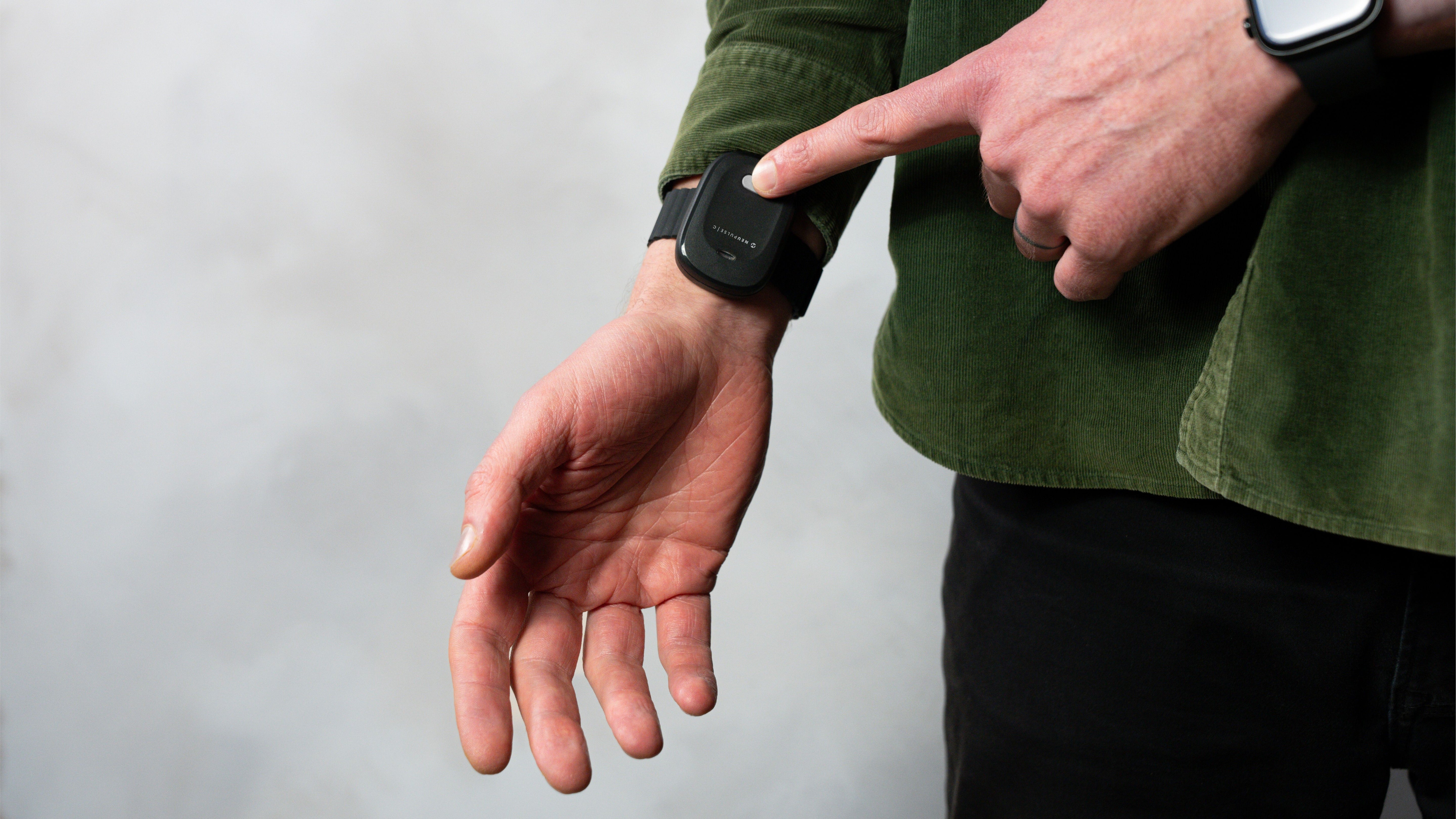 A man demonstrating how to activate a wearable stress relief device 